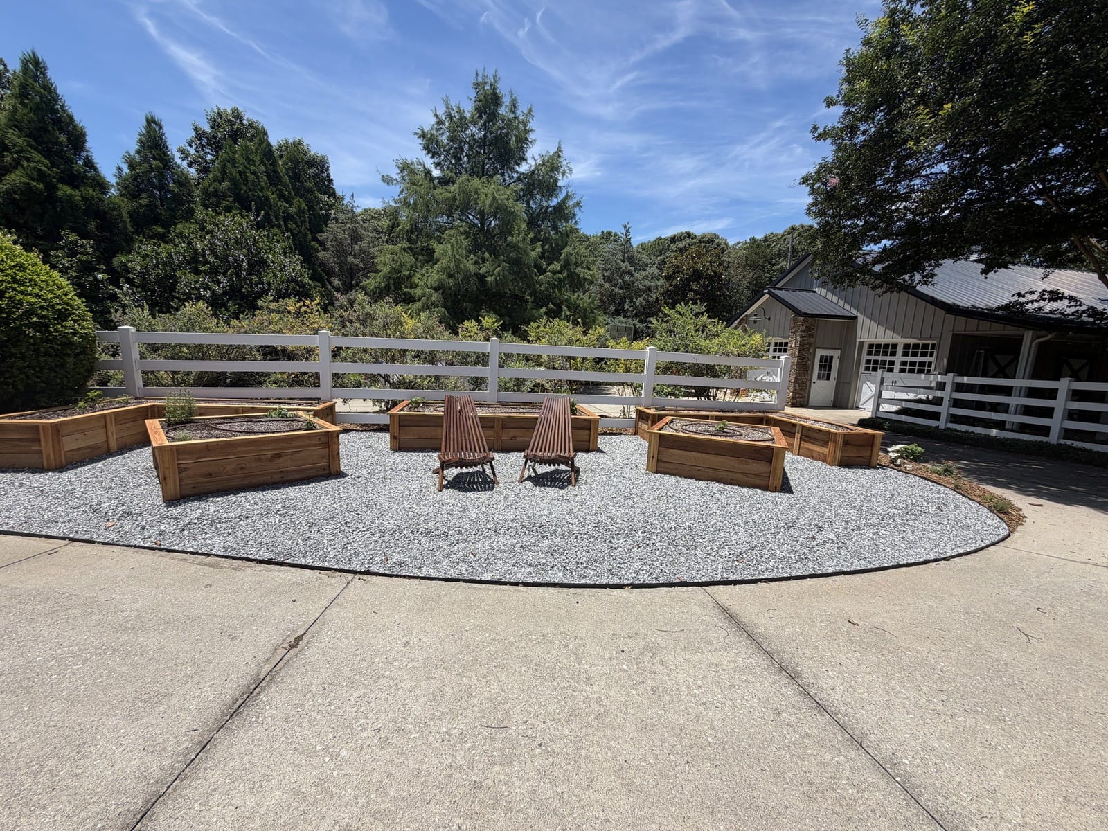 Angular raised beds and two chairs inside the white fence