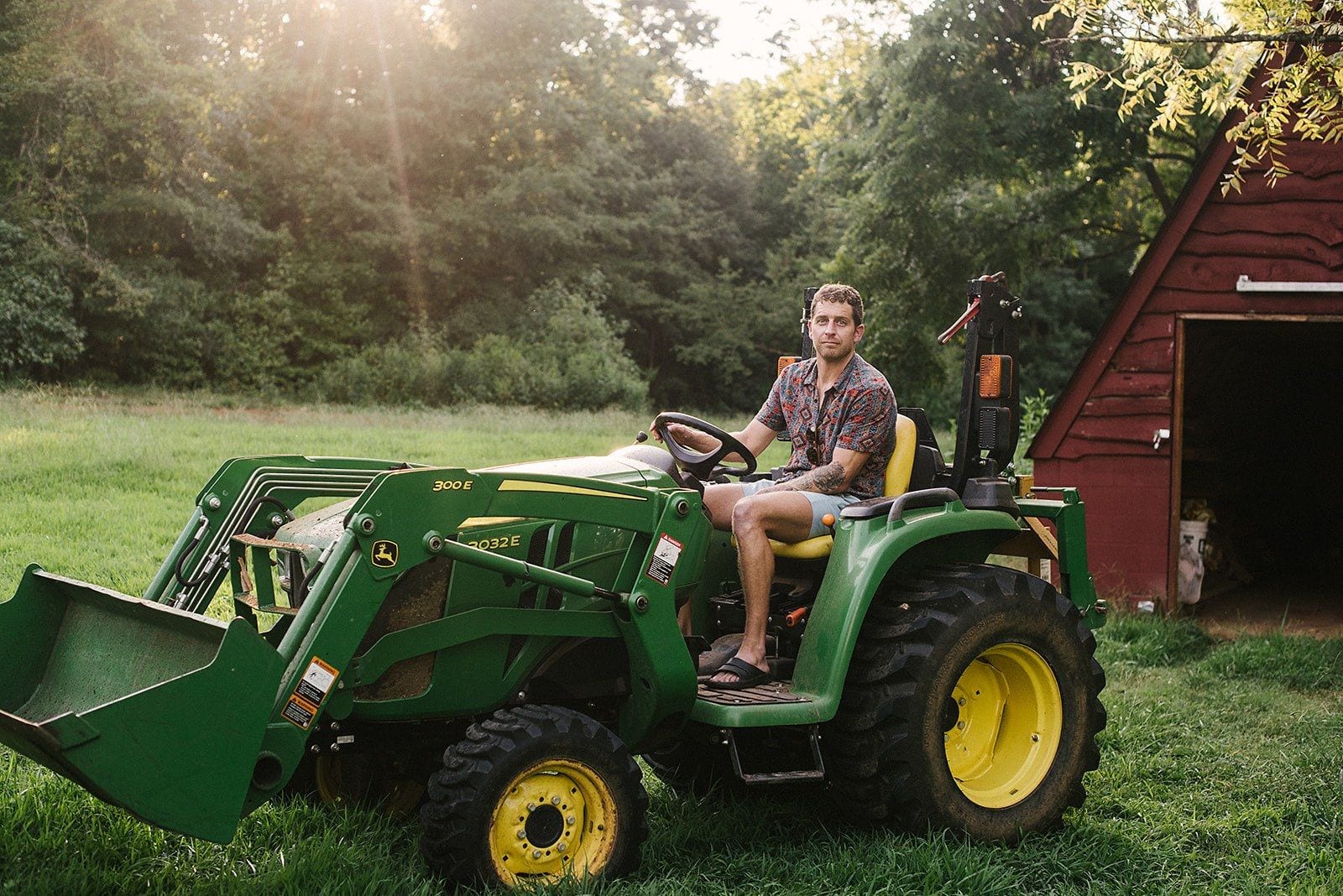 Chris on the John Deere at golden hour, red barn behind