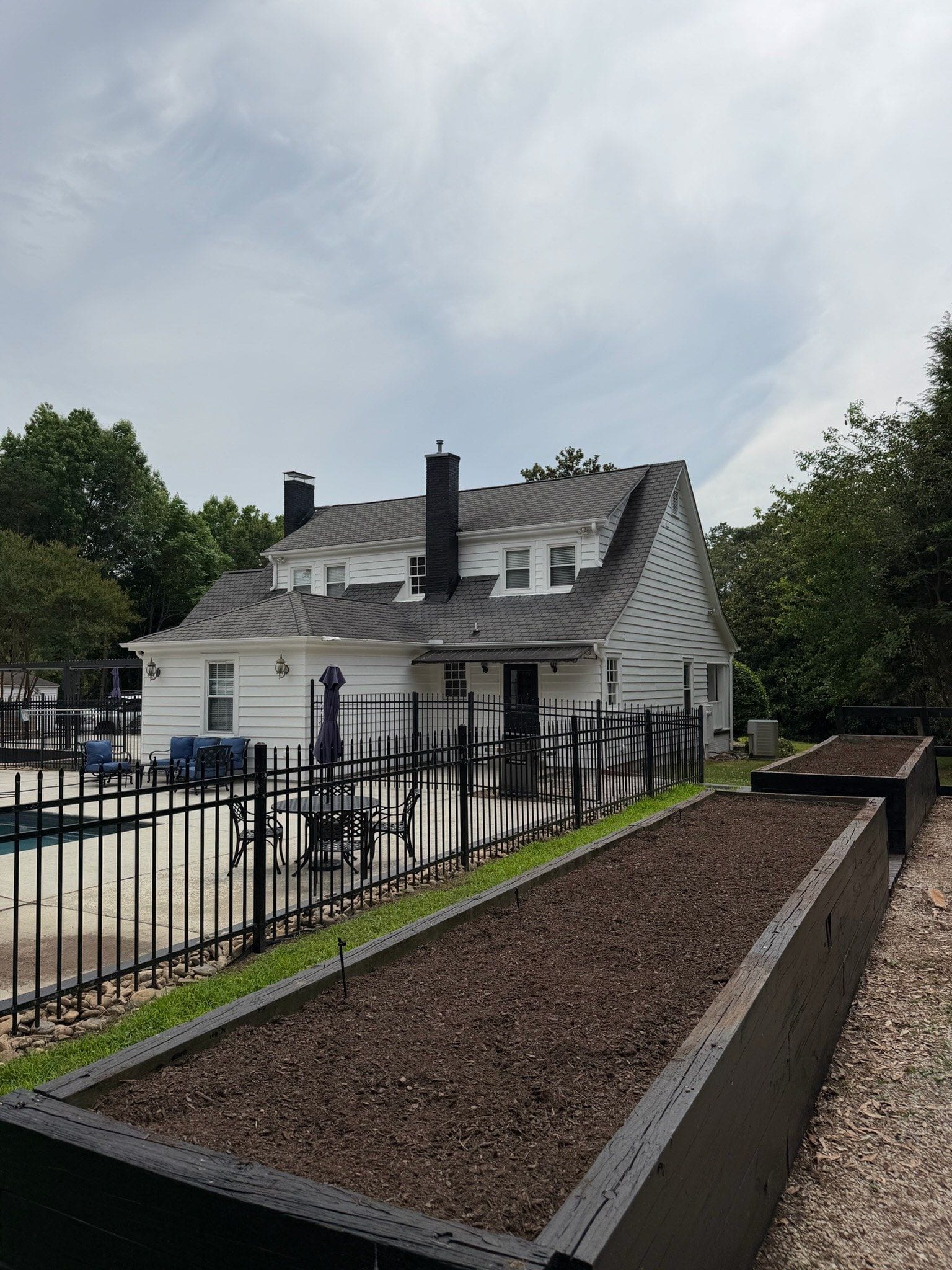 Poolside residential install, cedar beds behind a black iron fence