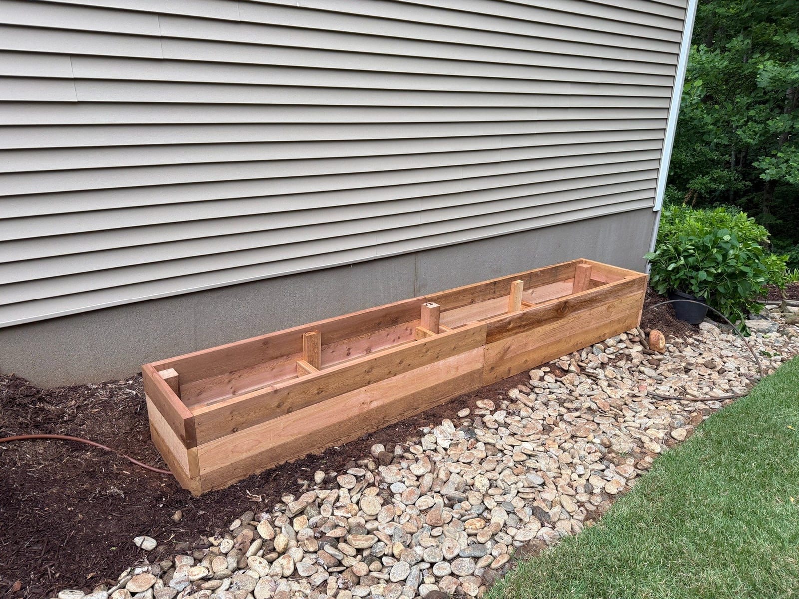 Cedar planter box under construction against a house foundation