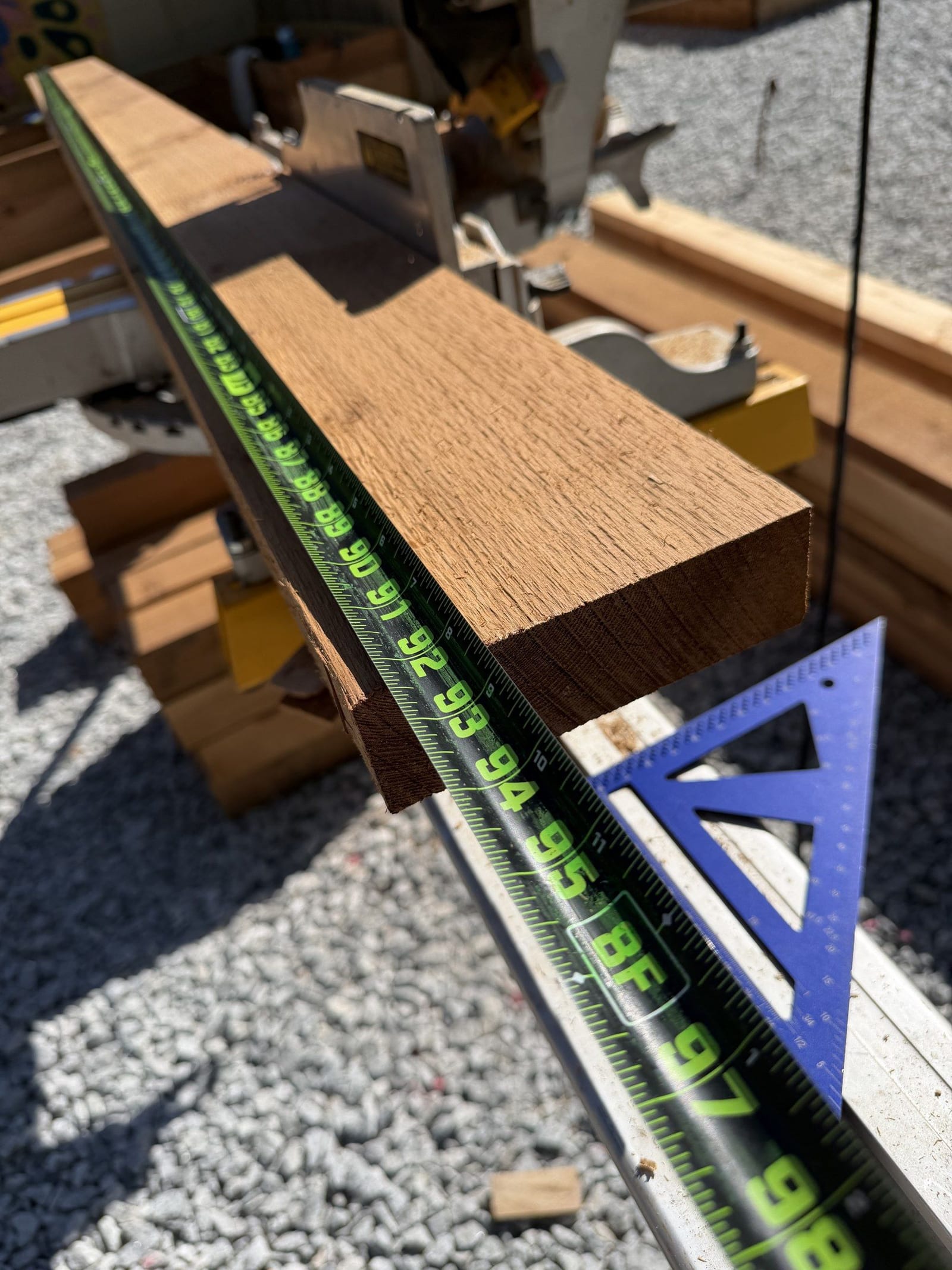 Cedar lumber on a measuring tape with a framing square, on site